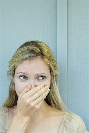 Woman covering mouth with hand, looking away, close-up Fotografie stock - Premium Royalty-Free, Codice: 632-01785240