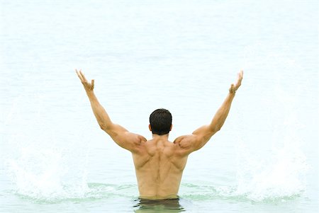 simsearch:632-05604352,k - Muscular man standing in swimming pool with arms raised, rear view Stock Photo - Premium Royalty-Free, Code: 632-01785353