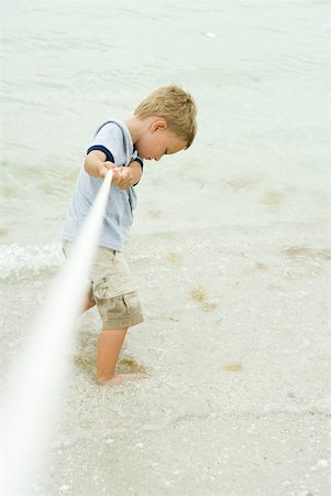 Boy playing tug-of-war at the beach, looking down Stock Photo - Premium Royalty-Free, Code: 632-01785361