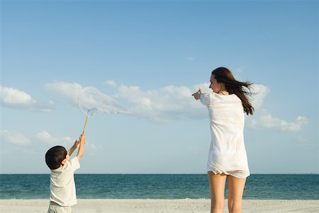 Woman and boy catching clouds, ocean horizon in distance Stock Photo - Premium Royalty-Free, Code: 632-01785405