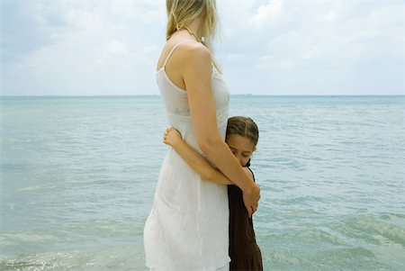 simsearch:633-05401631,k - Mother and daughter standing by water, hugging, ocean horizon in background Stock Photo - Premium Royalty-Free, Code: 632-01785414