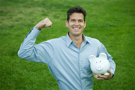 front view of a pig - Man holding piggy bank, raising fist and smiling at camera Stock Photo - Premium Royalty-Free, Code: 632-01785522