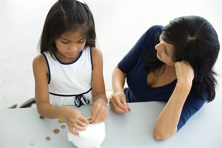 Mother and daughter putting coins in piggy bank together, high angle view Stock Photo - Premium Royalty-Free, Code: 632-01828318