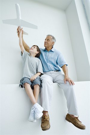 simsearch:649-06830154,k - Grandfather and grandson sitting side by side, holding up toy airplane together Foto de stock - Sin royalties Premium, Código: 632-01828639