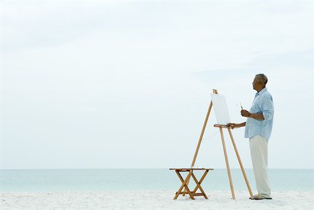 painter outdoors - Senior man standing in front of blank canvas at the beach, holding paint brushes Stock Photo - Premium Royalty-Free, Code: 632-02007228