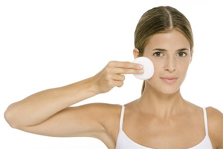 Woman holding up cotton pad to cheek, looking at camera Stock Photo - Premium Royalty-Free, Code: 632-02007939