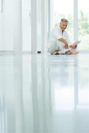 shine floor - Mature man sitting on the ground, holding book, smiling at camera Stock Photo - Premium Royalty-Free, Code: 632-02008062