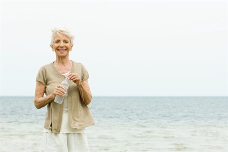 simsearch:632-05553667,k - Senior woman standing at the beach, holding bottle of water, smiling at camera Foto de stock - Sin royalties Premium, Código: 632-02008086