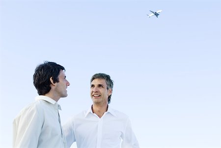 Two men talking to each other, airplane high in the background Stock Photo - Premium Royalty-Free, Code: 632-02128250