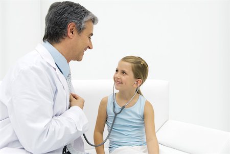 doctor with heart patient - Girl listening to doctor's heart with stethoscope, smiling Stock Photo - Premium Royalty-Free, Code: 632-02227617