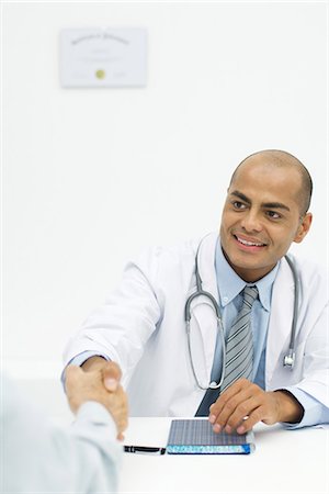 simsearch:400-04217553,k - Doctor shaking hands with patient, over the shoulder view Foto de stock - Royalty Free Premium, Número: 632-02227618