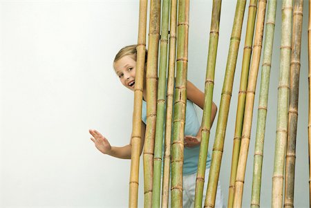 polish ethnicity (female) - Girl standing behind bamboo, smiling and waving at camera Stock Photo - Premium Royalty-Free, Code: 632-02227771