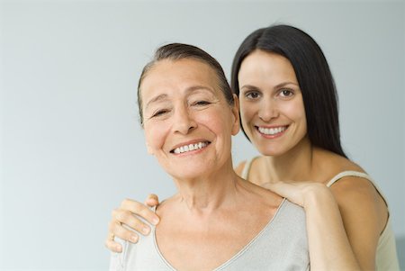 Woman behind senior mother, hands on shoulders, both smiling at camera, portrait Stock Photo - Premium Royalty-Free, Code: 632-02227925