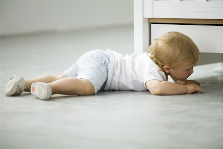 space exploration - Toddler crawling on the ground, peeking under crib, side view Stock Photo - Premium Royalty-Free, Code: 632-02282517