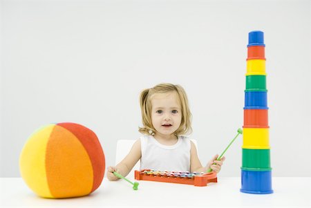 Toddler girl sitting with toys, playing xylophone, smiling at camera Fotografie stock - Premium Royalty-Free, Codice: 632-02282538