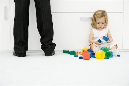 simsearch:695-03380035,k - Toddler girl sitting on the ground beside father's legs, playing with toys Foto de stock - Royalty Free Premium, Número: 632-02282548