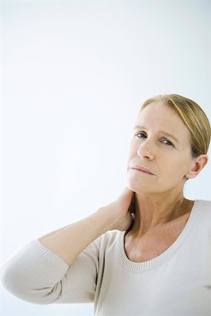 Mature woman rubbing her neck, looking at camera Stock Photo - Premium Royalty-Free, Code: 632-02282638