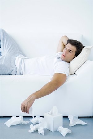 Man lying on sofa, discarded tissues on the floor beside him Stock Photo - Premium Royalty-Free, Code: 632-02282646