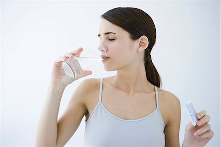 Woman drinking effervescent water, holding medicine packet Stock Photo - Premium Royalty-Free, Code: 632-02282641