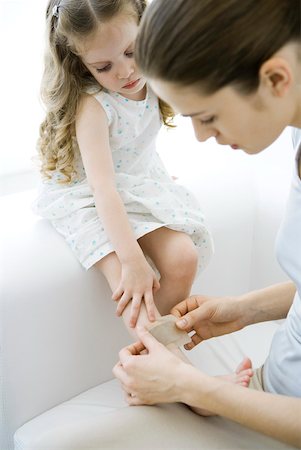 Mother putting adhesive bandage on young daughter's leg Stock Photo - Premium Royalty-Free, Code: 632-02282652