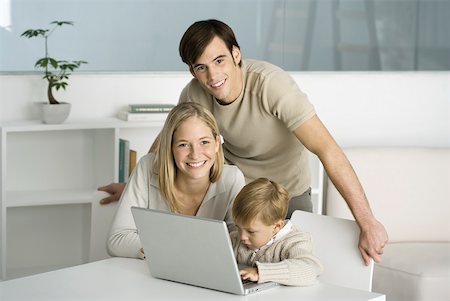 Family gathered around laptop computer, little boy typing, parents smiling at camera Stock Photo - Premium Royalty-Free, Code: 632-02282866