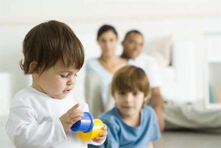 Toddler girl playing with toys, family watching in background Foto de stock - Sin royalties Premium, Código: 632-02282904