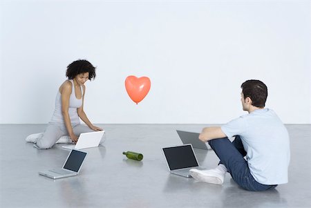 sitting on the ground with a laptop - Man and woman sitting with laptop computers, playing "spin the bottle" Stock Photo - Premium Royalty-Free, Code: 632-02283055