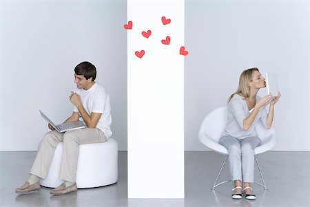 Femme embrasse l'ordinateur portable, l'homme regardant son propre ordinateur portable et souriant, coeurs en l'air entre eux Photographie de stock - Premium Libres de Droits, Code: 632-02283066