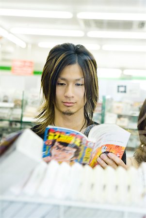 Young Japanese man reading comic book in store Stock Photo - Premium Royalty-Free, Code: 632-02344445