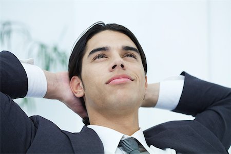 Young businessman leaning back with hands behind head, looking up, portrait Stock Photo - Premium Royalty-Free, Code: 632-02344691