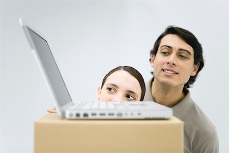 Man and woman peeking at laptop computer sitting on top of cardboard box Stock Photo - Premium Royalty-Free, Code: 632-02344717