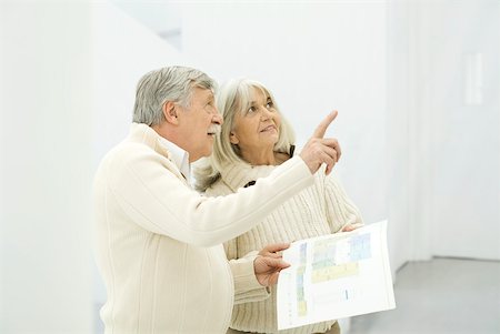 senior couple interior design - Senior couple standing together, man holding floor plans and pointing up Stock Photo - Premium Royalty-Free, Code: 632-02344953
