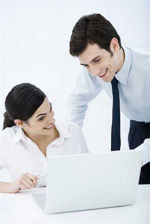 simsearch:632-02128084,k - Professional man looking over female colleague's shoulder at laptop computer, both smiling Foto de stock - Sin royalties Premium, Código: 632-02345112