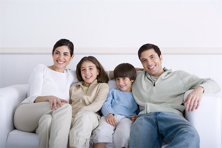 simsearch:695-03390229,k - Family sitting together on sofa, smiling Foto de stock - Royalty Free Premium, Número: 632-02345176
