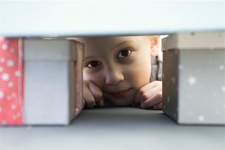 present hide - Little boy hiding behind pile of presents, peeking at camera Stock Photo - Premium Royalty-Free, Code: 632-02416109