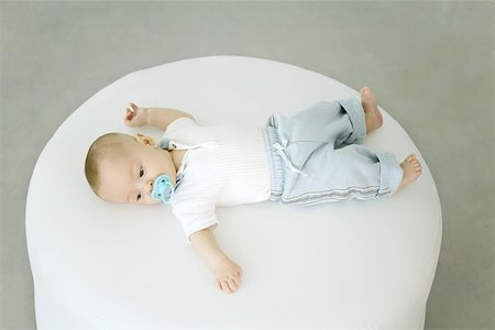 Baby lying on ottoman, sucking on pacifier, high angle view Stock Photo - Premium Royalty-Free, Code: 632-02416243