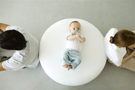 Infant lying on ottoman, mother and father sitting with backs turned, overhead view Foto de stock - Sin royalties Premium, Código: 632-02416260