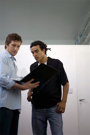 reliure à anneaux - Hommes debout ensemble à la recherche sur le contenu du classeur Photographie de stock - Premium Libres de Droits, Code: 632-02644882