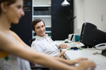 Man sitting at desk, smiling at female colleague Stock Photo - Premium Royalty-Free, Code: 632-02644931