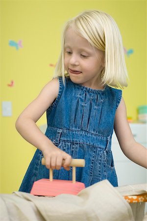 Little girl playing with toy iron and ironing board Stock Photo - Premium Royalty-Free, Code: 632-02645136