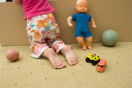 Little girl kneeling on floor with toys, rear view, cropped Stock Photo - Premium Royalty-Free, Code: 632-02645139