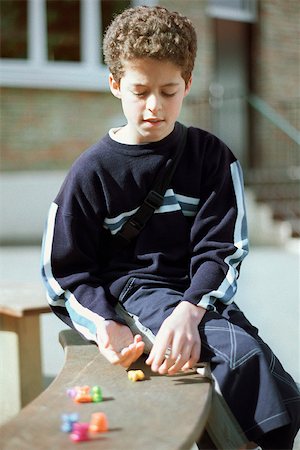 Boy sitting on bench, playing game Foto de stock - Sin royalties Premium, Código: 632-02690111