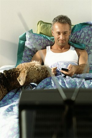 simsearch:696-03401356,k - Man watching TV in bed with dog Stock Photo - Premium Royalty-Free, Code: 632-02744714