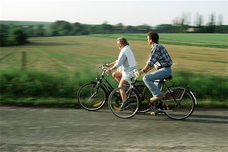 side view of a guy riding a bike - Couple riding bicycles through countryside Stock Photo - Premium Royalty-Free, Code: 632-02744717