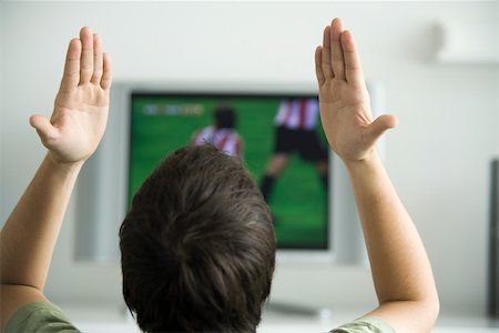 Male watching sports match on television, hands raised in air, rear view Stock Photo - Premium Royalty-Free, Code: 632-02744882