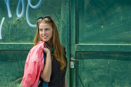 Fashionable young woman standing in front of graffitied door, jacket slung over shoulder Foto de stock - Sin royalties Premium, Código: 632-02745014