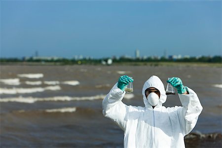 Person in protective suit holding up flasks filled with polluted water Foto de stock - Sin royalties Premium, Código: 632-02745077