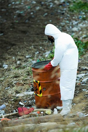 Personne en tenue de protection transportant des barils de déchets dangereux Photographie de stock - Premium Libres de Droits, Code: 632-02745073