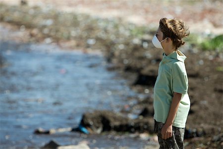 simsearch:632-02745100,k - Boy wearing pollution mask, standing on polluted shore Foto de stock - Sin royalties Premium, Código: 632-02745099