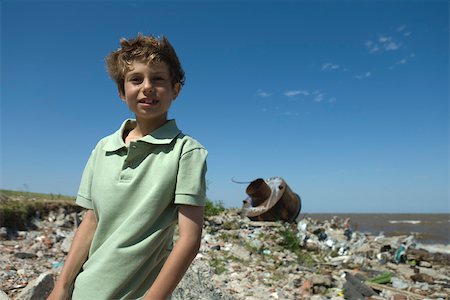 simsearch:632-02745100,k - Boy standing on polluted shore, smiling at camera Foto de stock - Sin royalties Premium, Código: 632-02745104